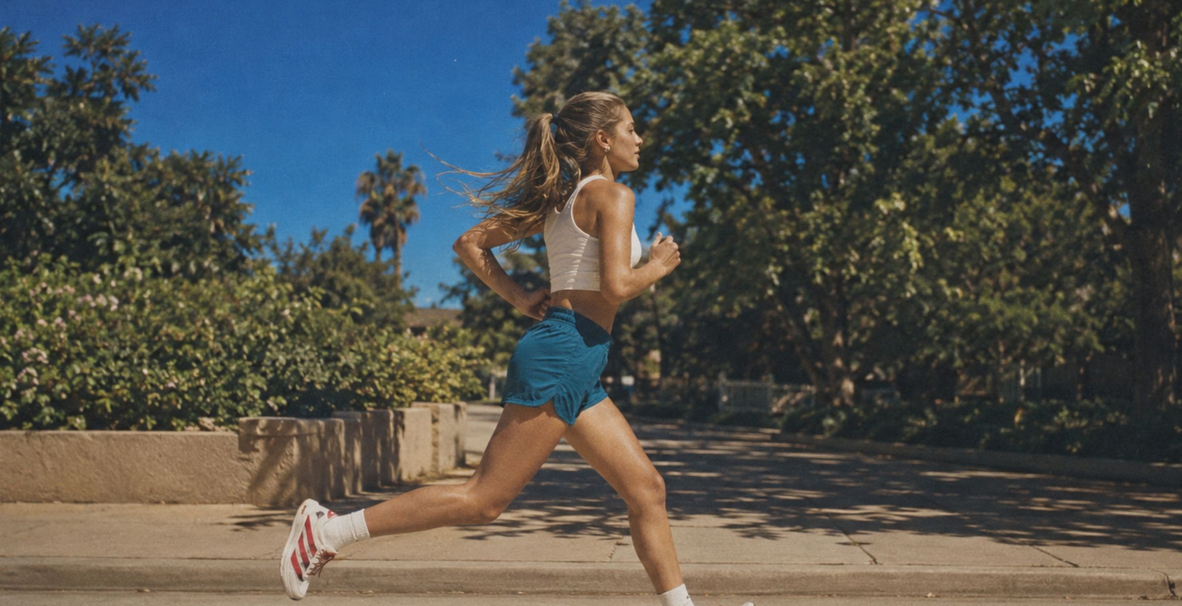 A woman running along a tree-lined street on a sunny day