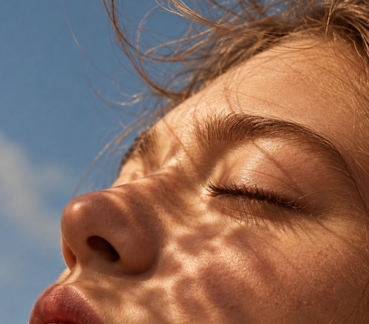 Close-up of a face with eyes closed in dappled sunlight