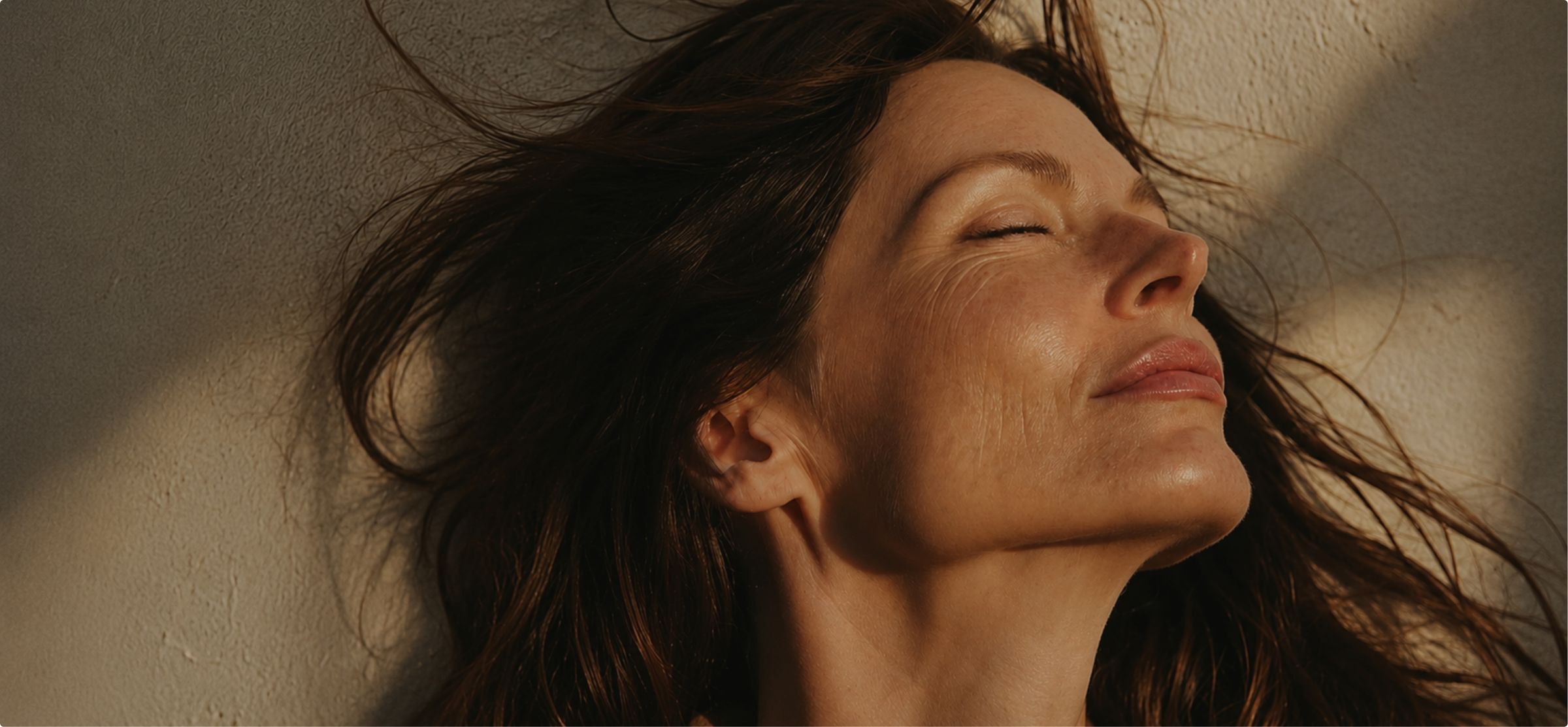 A woman with her eyes closed, face lifted to warm sunlight