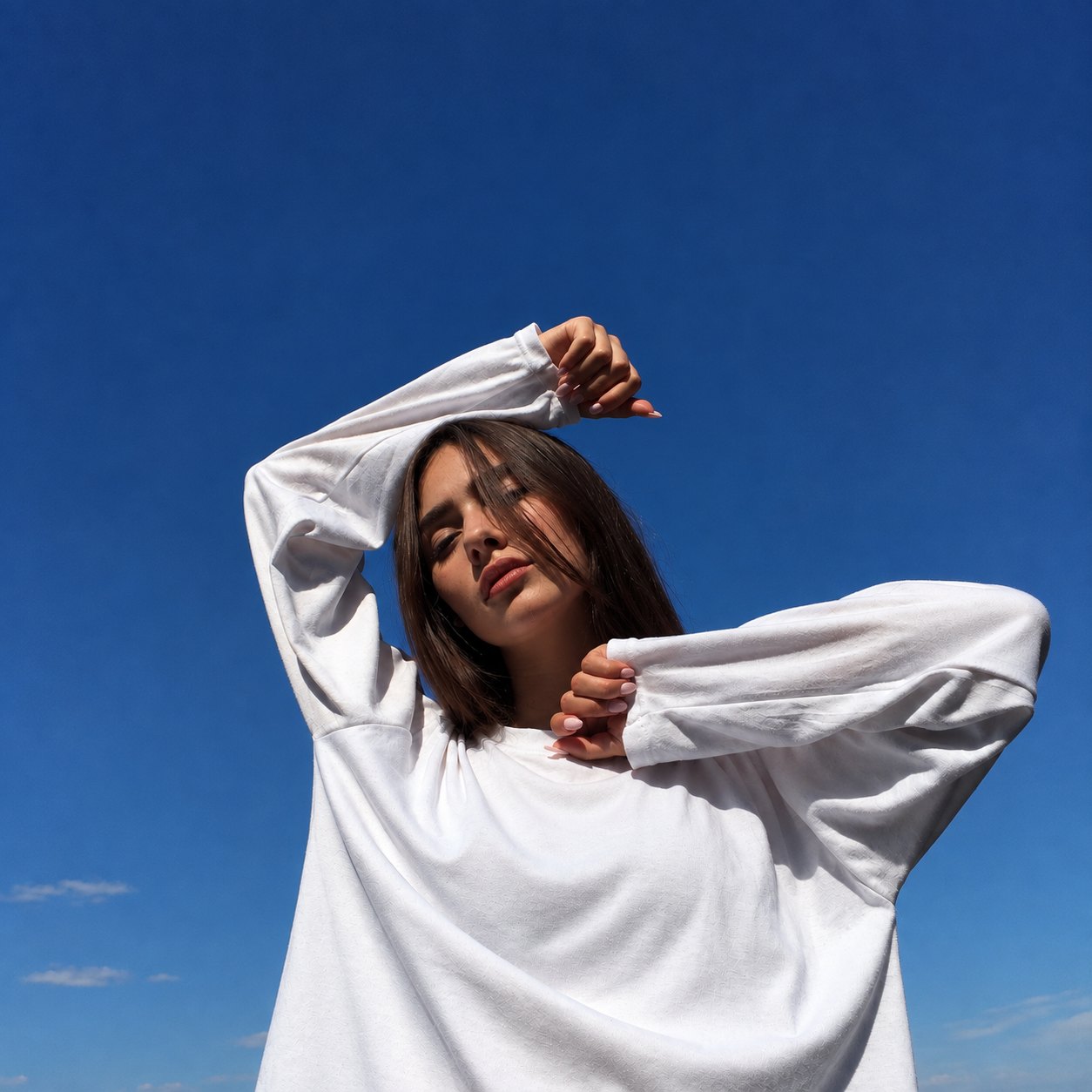 A woman in a white sweater under a blue sky