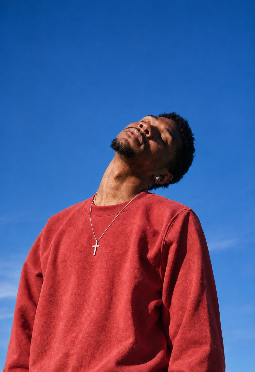 A man in a red sweater with his face to the sun