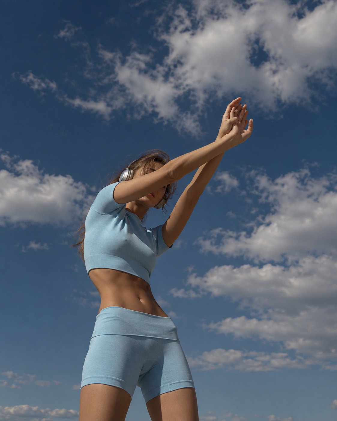 A woman stretching under a blue sky