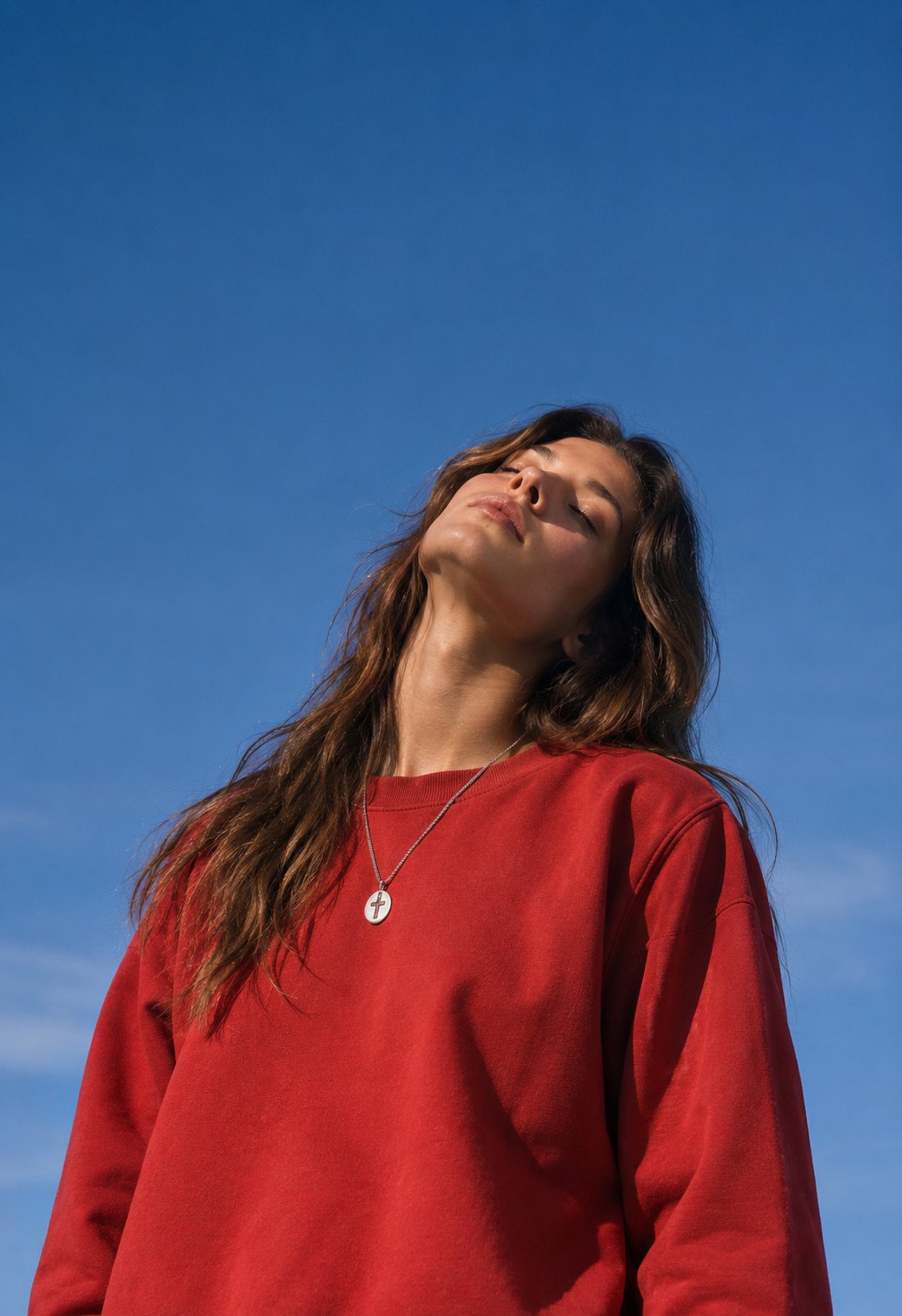 A woman in a red sweater with her face to the sun